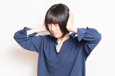 洗濯機からの異音で耳を塞ぐ女性